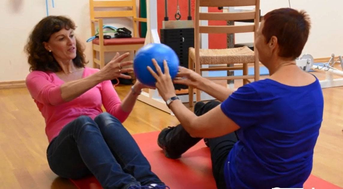 To personer gjør øvelse med ball sittende